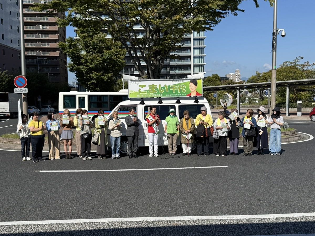 選挙カーの前に並び、チラシを手に応援する支援者の皆さん。