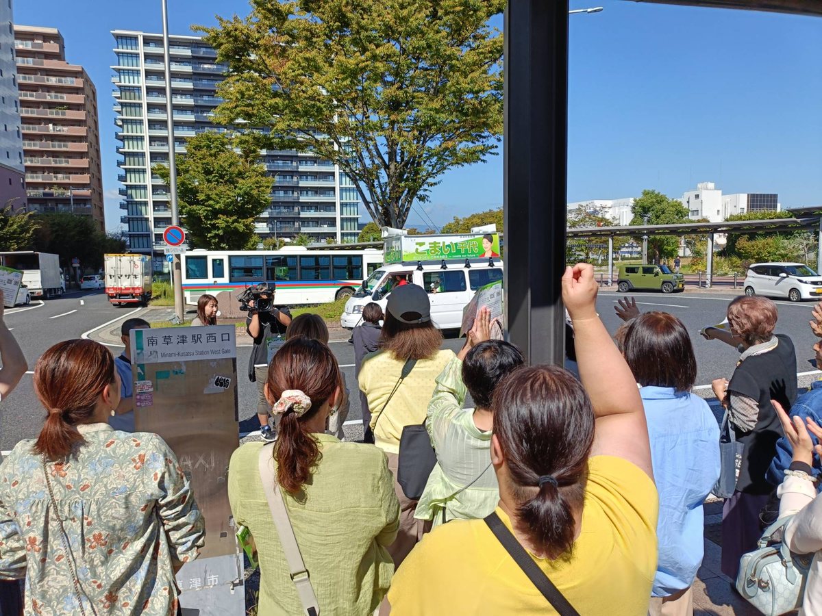 南草津駅西口で、選挙カーに向かって手を振り、こぶしを上げて応援する市民の皆さん。